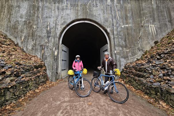 Cyclists are shown in front of the Big Savage Tunnel on the Great Allegheny Passage.