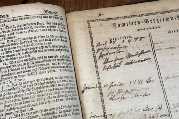 Two open pages of an old German book. The left page contains printed text in German. The right page, titled "Familien-Verzeichniss" (Family Register), has handwritten entries, including names, dates, and possibly family relationships, with faded cursive writing.