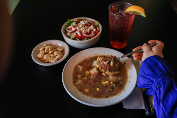 Table with a bowl of soup, crackers, salad, and beverage with a lemon