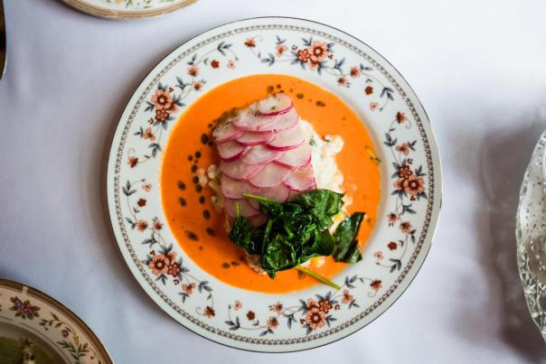 Floral decorative plate with orange soup, radish, and greens