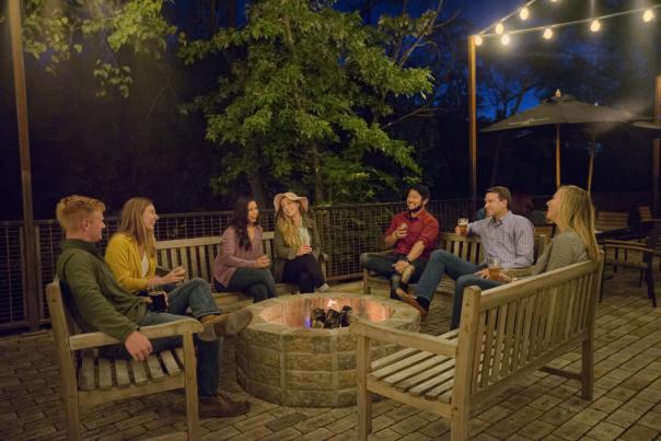 Group of friends sitting at fire pit outside of Goodfellas Pizza.