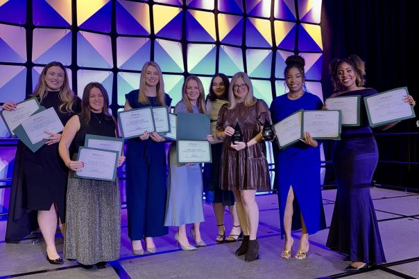 8 women standing on stage holding awards