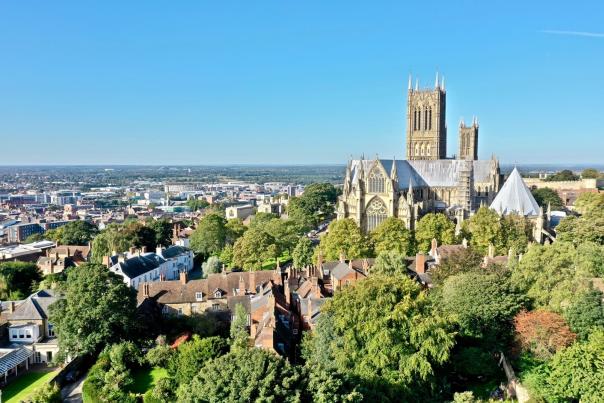 Lincoln Cathedral from a distance, looking over residential houses and green trees