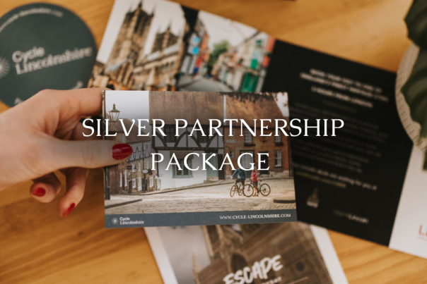 A hand holding a business cards and a table with business cards behind.