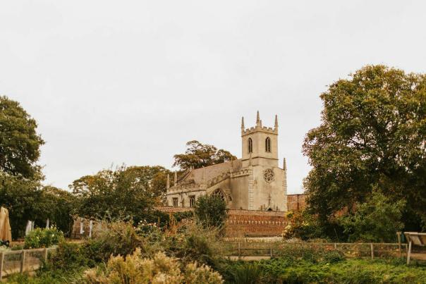 A lush garden with wooden walkways and a church in the background.