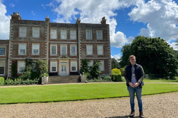 a historic house 'Gunby Hall' with a man stood in front smiling for the camera