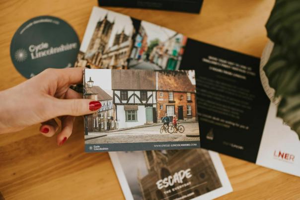 a postcard in a woman's hand with for 'Cycle Lincolnshire'