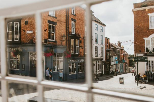a view from inside a window of a pub and courtyard with people walking