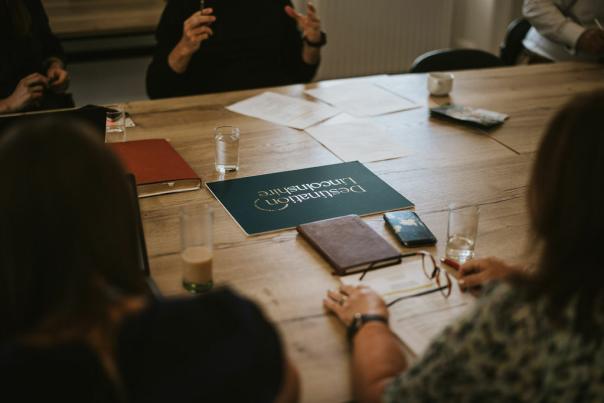 over the shoulder shot of people sat at a wooden table with a destination lincolnshire logo on