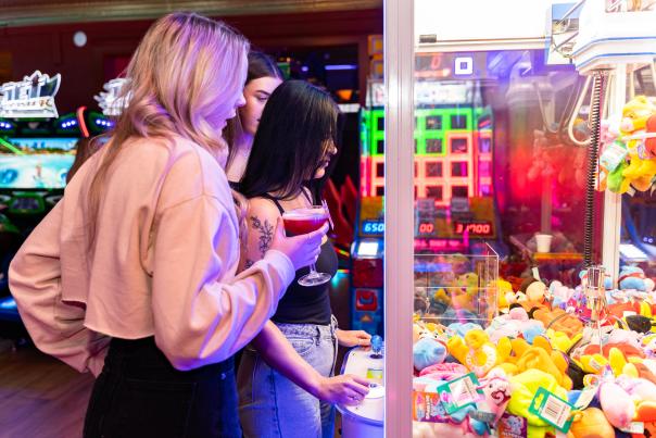 a group of friends playing with the toy grabbing machine in an indoor amusement area