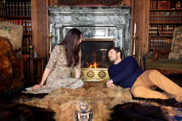 Woman and man laying on rug next to fireplace