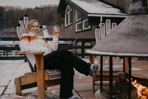Woman relaxing by fire at ski resort