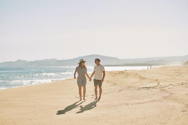 pareja heterosexual caminando en la playa tomados de la mano