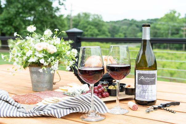 Two glasses of Fleetwood Farm Winery Pinot Noir with a charcuterie spread on an outdoor deck in Leesburg, Virginia