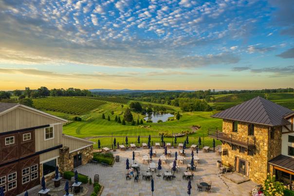 Aerial view of Stone Tower Winery's outdoor patio and rolling vineyard at sunset in Leesburg, Virginia.
