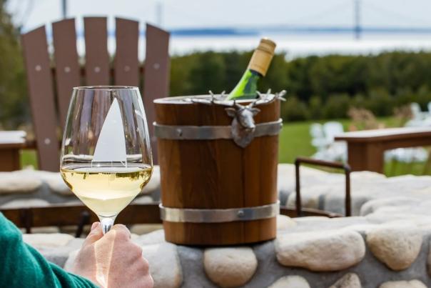 A glass of wine with a bottle in a bucket of ice is set against the Mackinac Bridge