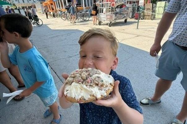 A boy puts a giant cookie into his mouth Mackinac Island Cookie Co. Arnold Transit ferry dock