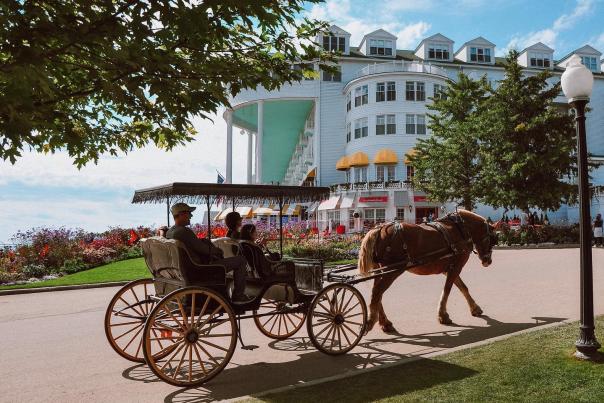 A horse-drawn carriage passes Mackinac Island’s Grand Hotel on a sunny summer day