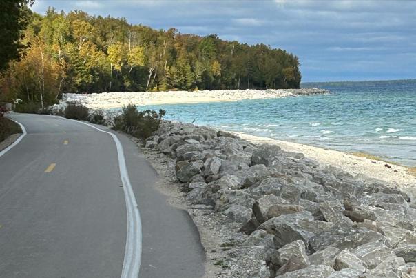 An empty Mackinac Island road along the shoreline with rocks between the roadway and the water