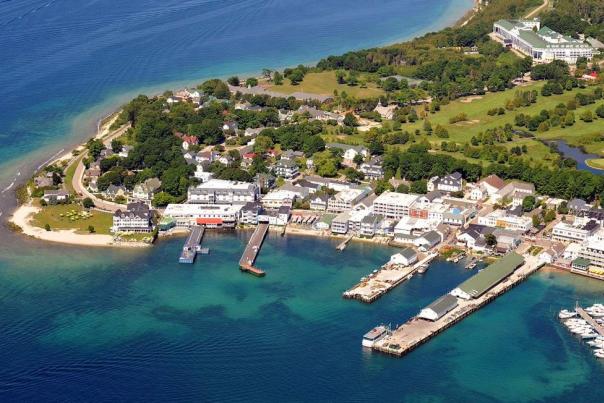 Aerial view of downtown Mackinac Island with docks jutting into water and Grand Hotel on the bluff