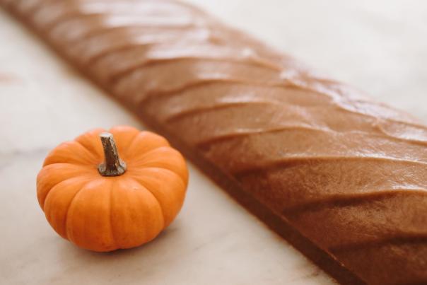 A loaf of Mackinac Island fudge on a marble slab next to a tiny orange pumpkin