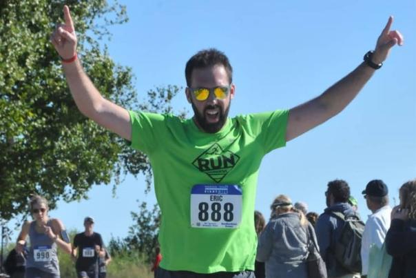 A runner in a Mackinac Island road race raises his arms at the finish line.