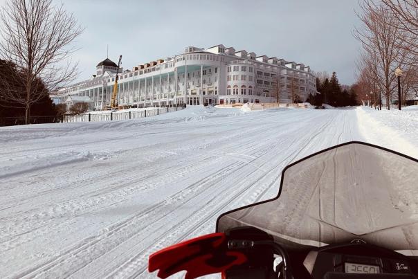 A snowmobile makes its way up snowy Cadotte Avenue toward Grand Hotel on Mackinac Island