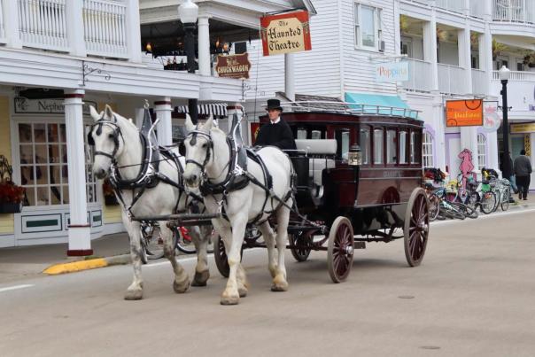 A two-horse carriage passes the Haunted Theatre on Mackinac Island’s Main Street