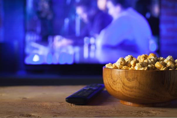 A bowl of popcorn sitting on the table in front of a TV
