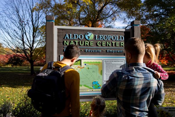 Two dads and their daughters reading a sign at the Aldo Leopold Nature Center
