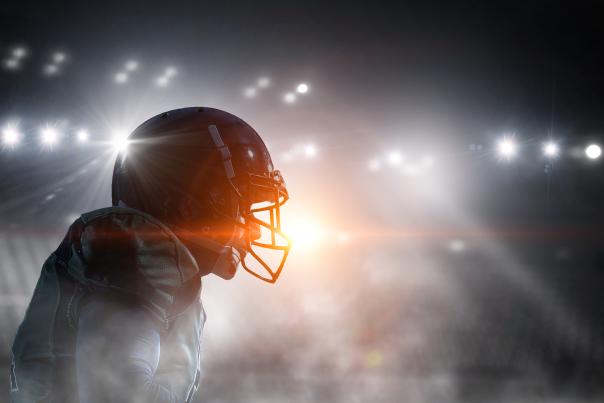 A football player stands in the bright lights of a stadium