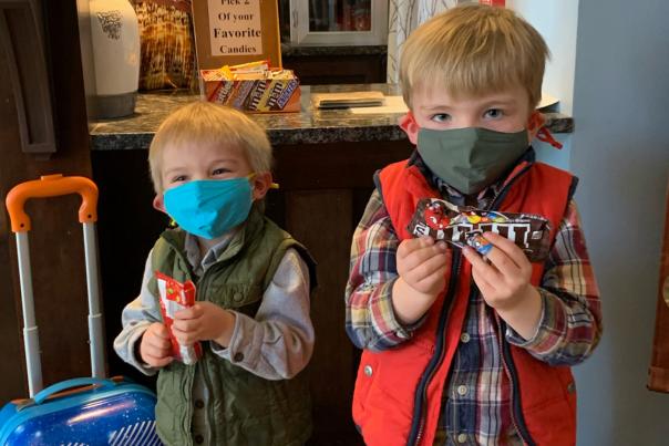 Two children wearing masks hold individual bags of candy