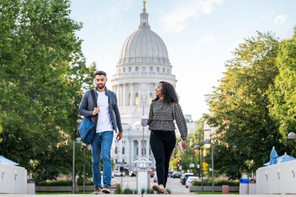 Two people walking in Madison WI with State Capitol Building in background
