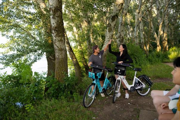 Two cyclists high five each other in front of Lake Monona and Olin Park