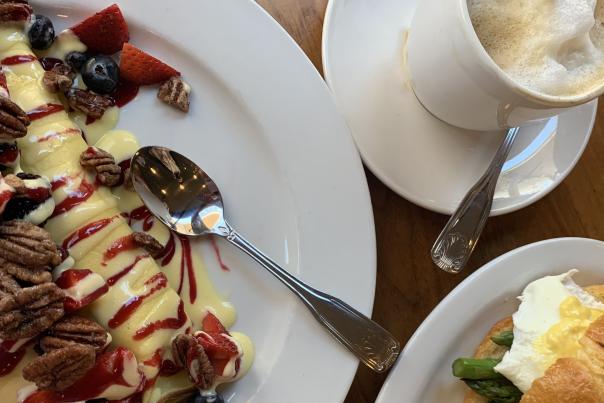 Crepe with strawberries, pecans, blueberries, and cream with a cappuccino on the side