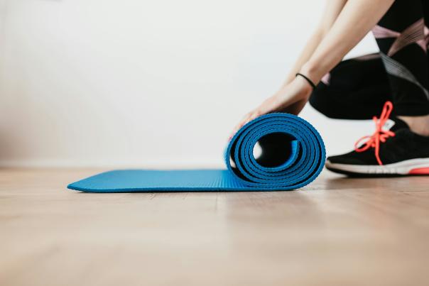 Person rolling up a yoga mat after a pilates session