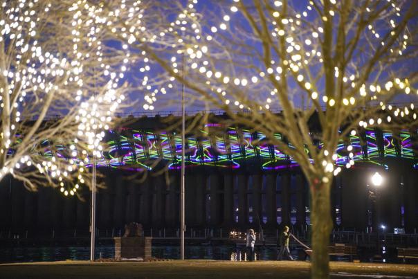 Trees lit with holiday lights in front of the laser lights display on the Ore Dock