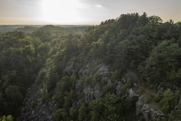 A couple overlooking the forested view from a rock outcropping on the RAMBA Trails in Ishpeming, MI
