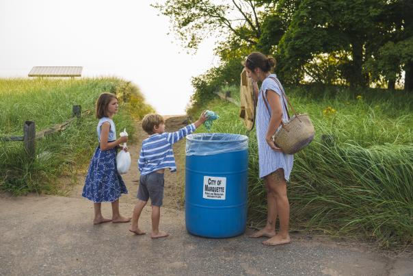 A kid putting trash into city garbage can at the beach