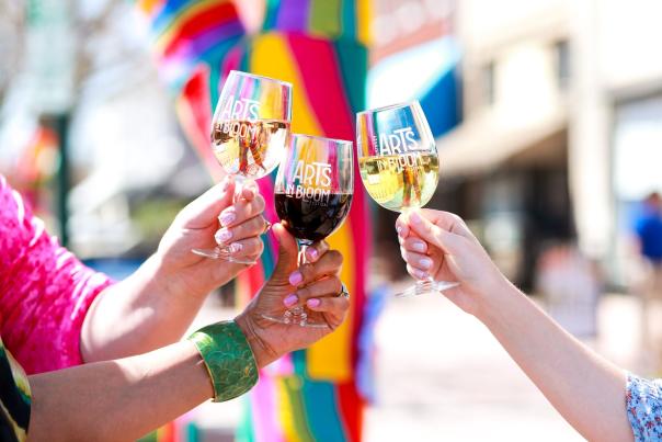 Three people holding wine glasses that say Arts in Bloom