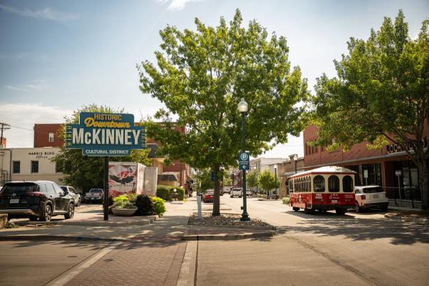 Historical Downtown McKinney welcome sign and red and white trolly on street