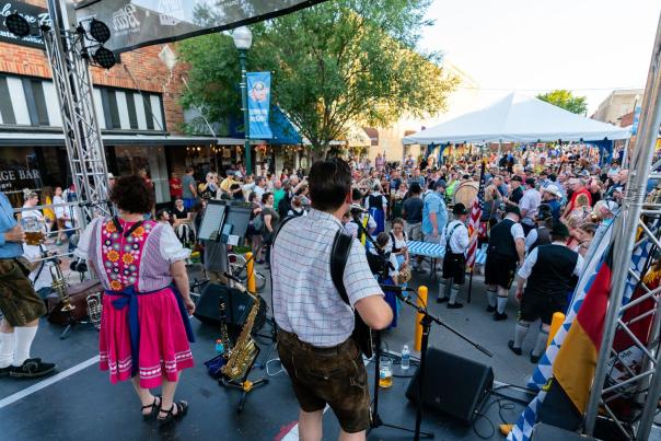 Stage with people playing instruments and singing toward a crowd at a festival