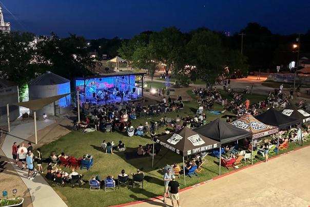 outdoor covered stage with night sky and people in lawn chairs