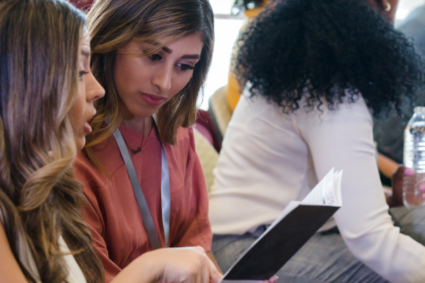 2 mixed race women look at an event programme in Cambridge, UK