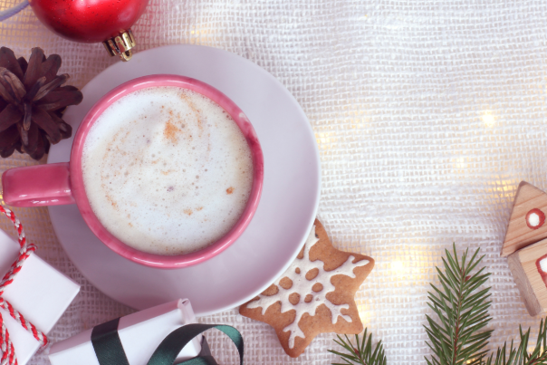 Frothy coffee in a coral up on a white saucer with Christmas cookies