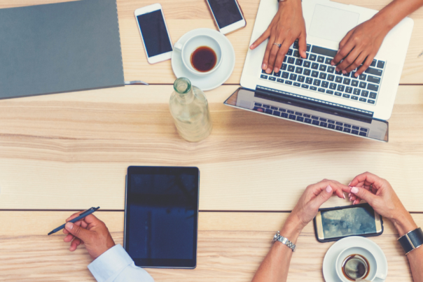 5 people sat round a wooden table having a business meeting