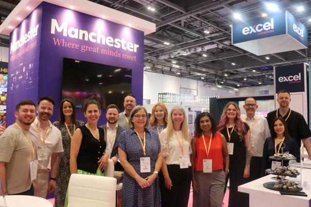 Marketing Manchester team members and partner representatives standing together on the Manchester exhibition stand at The Meetings Show 2026, with branded signage and ExCeL London visible in the background.