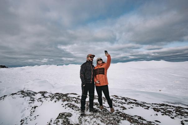 A couple standing on an ice formation on the shoreline of Lake Superior in the Upper Peninsula of Michigan.