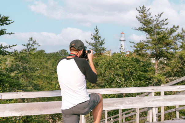 A man photographing the Whitefish Point Light, located in the Upper Peninsula of Michigan