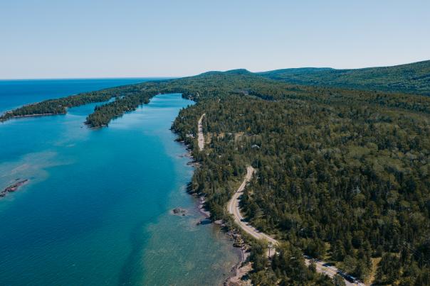 A winding road surrounded by Lake Superior and forest in the Upper Peninsula of Michigan